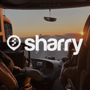 логотип і назва компанії Sharry на фоні переднього великого вікна автобуса, що їде ввечері по дорозі